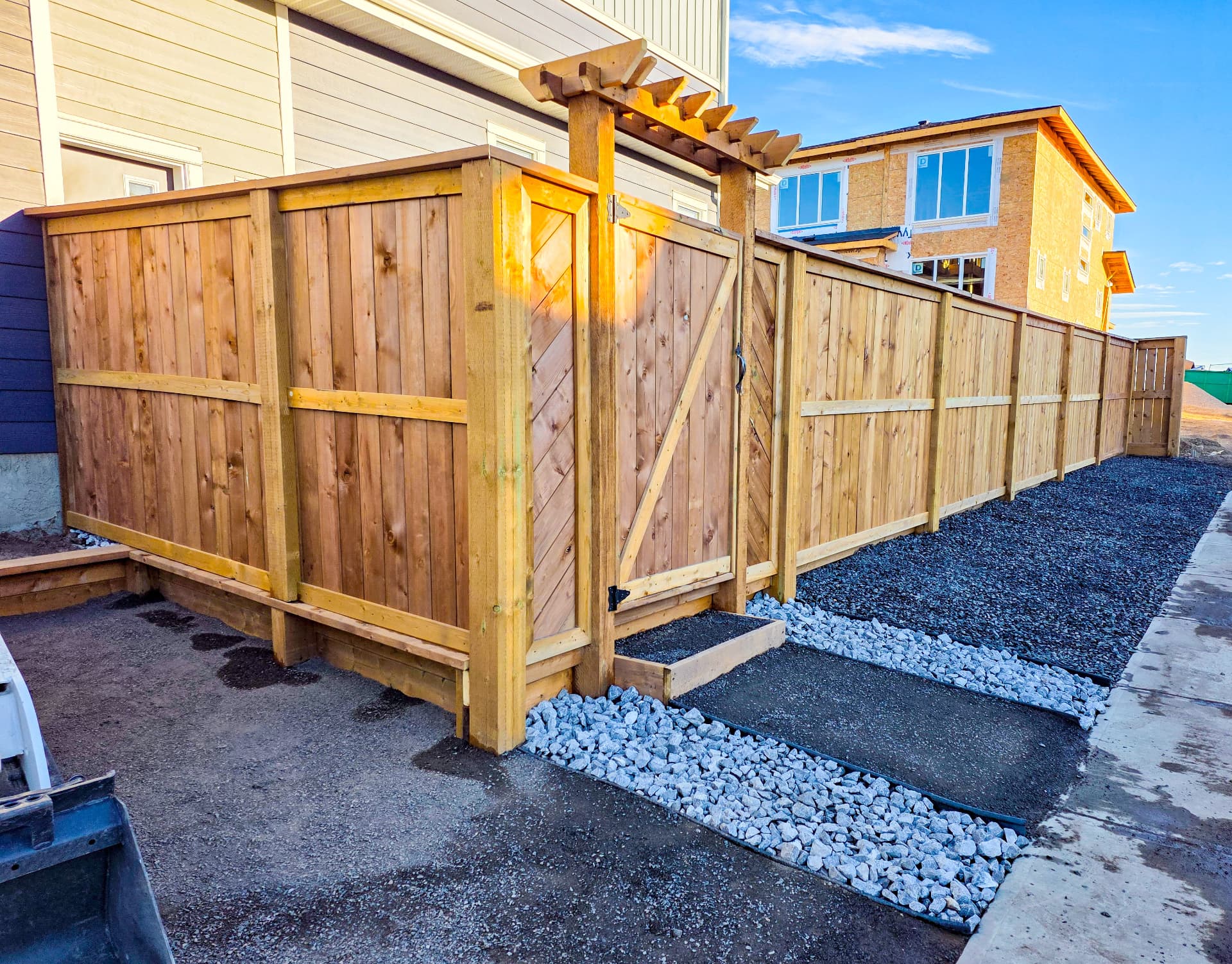 Cedar fence with pergola-topped gate and gravel walkway