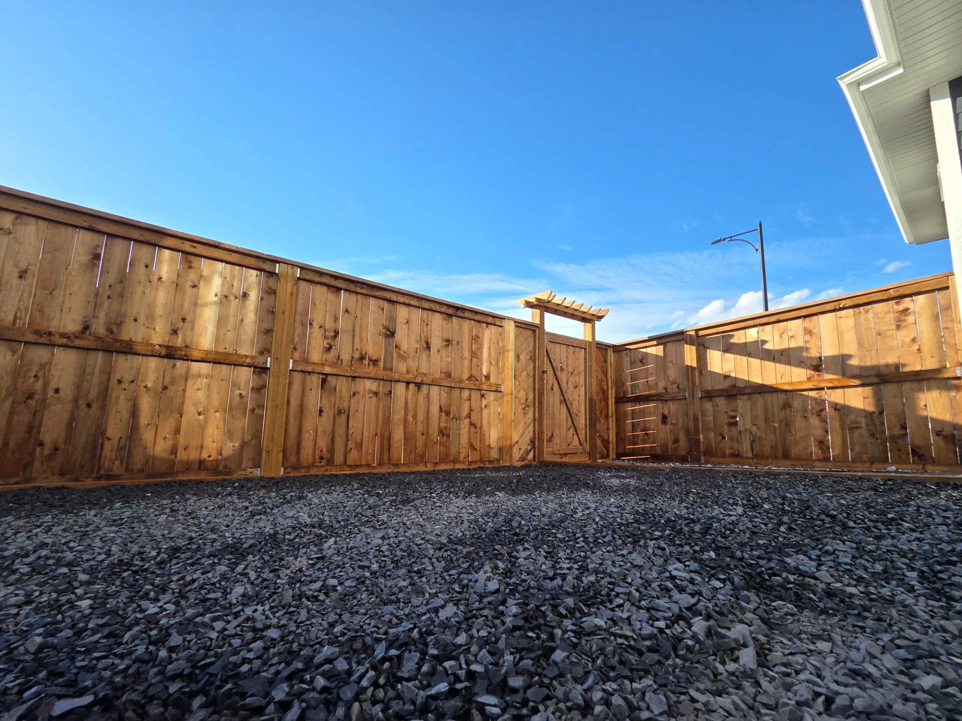 Fenced backyard with arbour gate and gravel groundcover