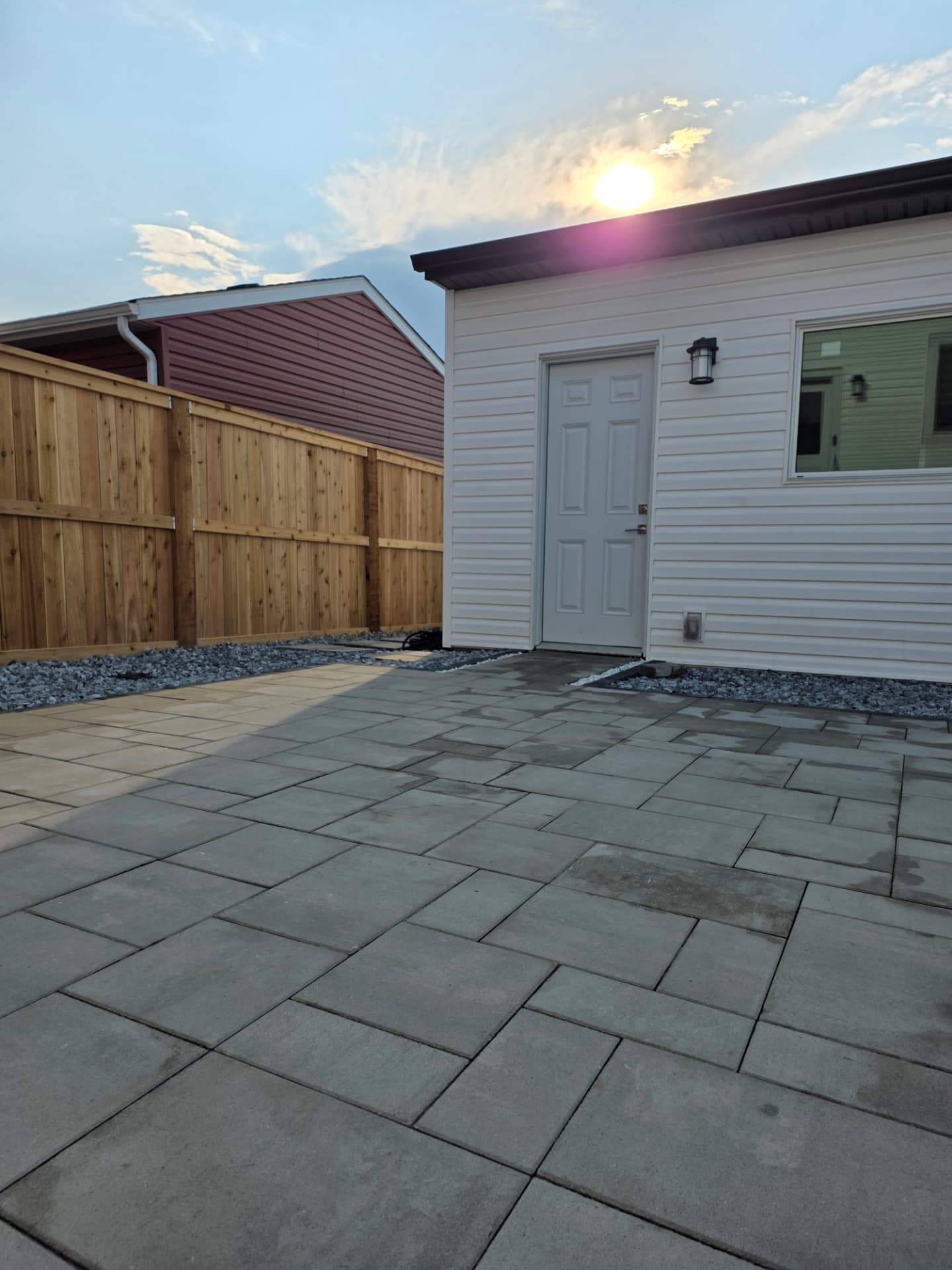 Large paver patio between a garage and cedar fence at sunset