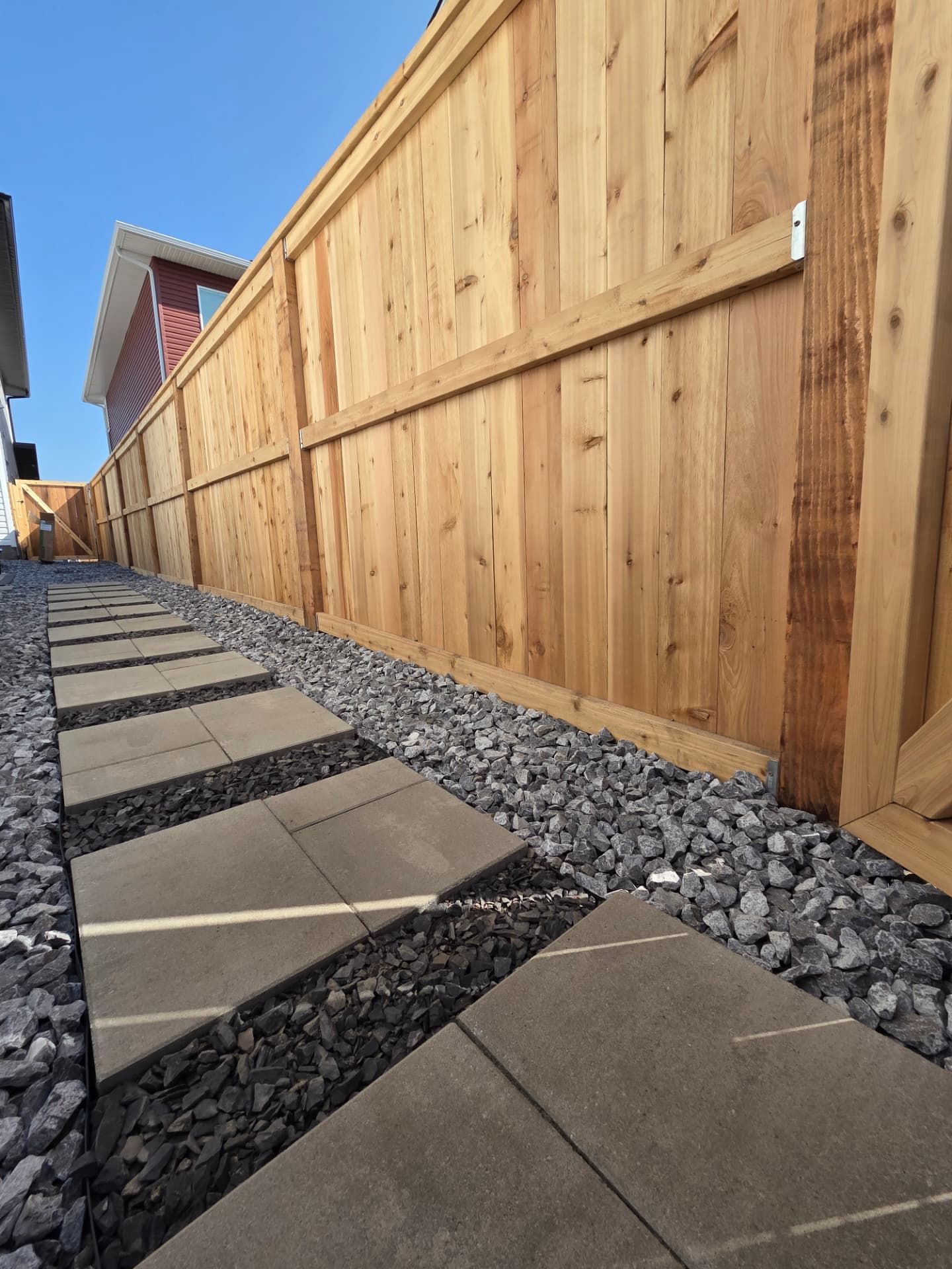 Cedar privacy fence beside a paver stepping-stone walkway