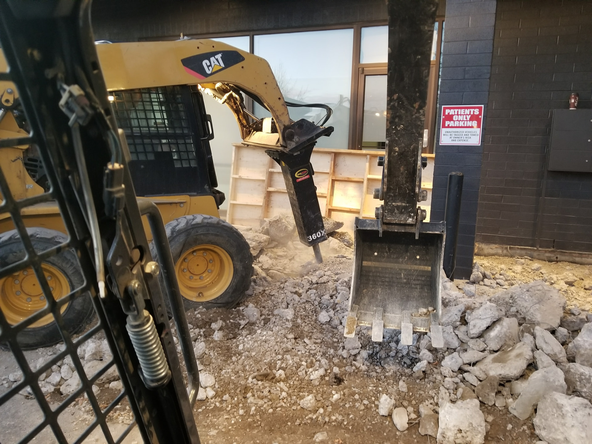 Skid steer with hydraulic breaker removing concrete at a commercial site